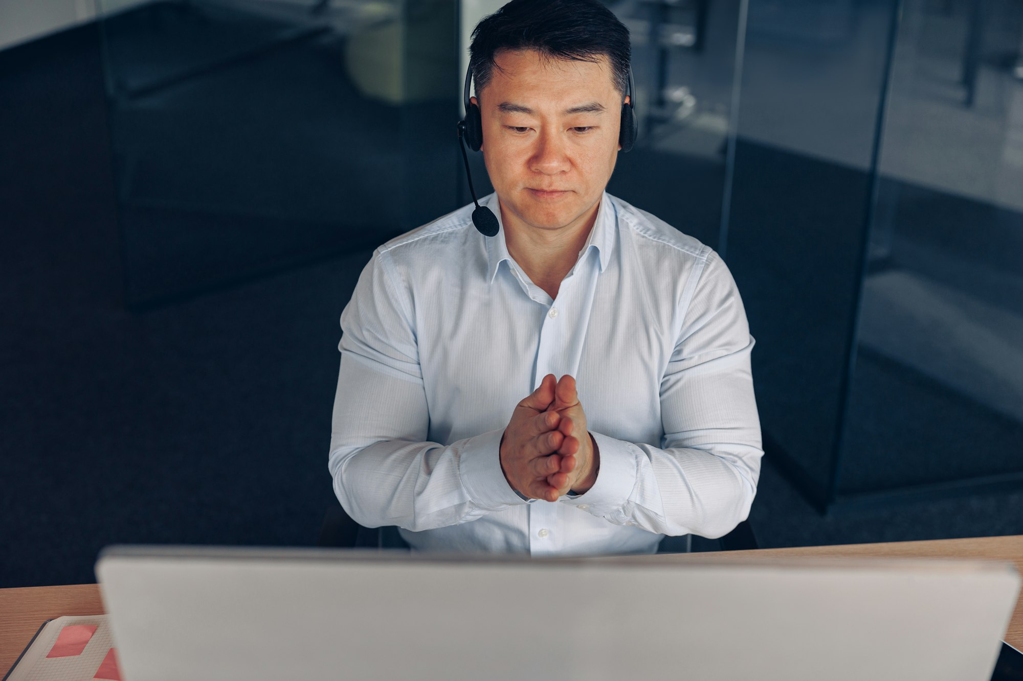 Asian businessman in headphones working on computer in modern coworking